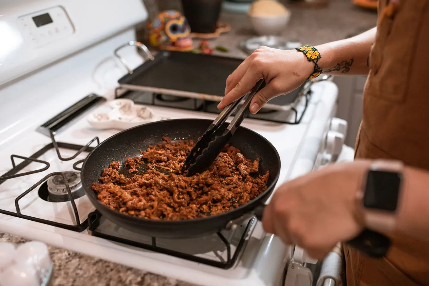Hackfleisch wird mit der Zange in der Pfanne gewendet