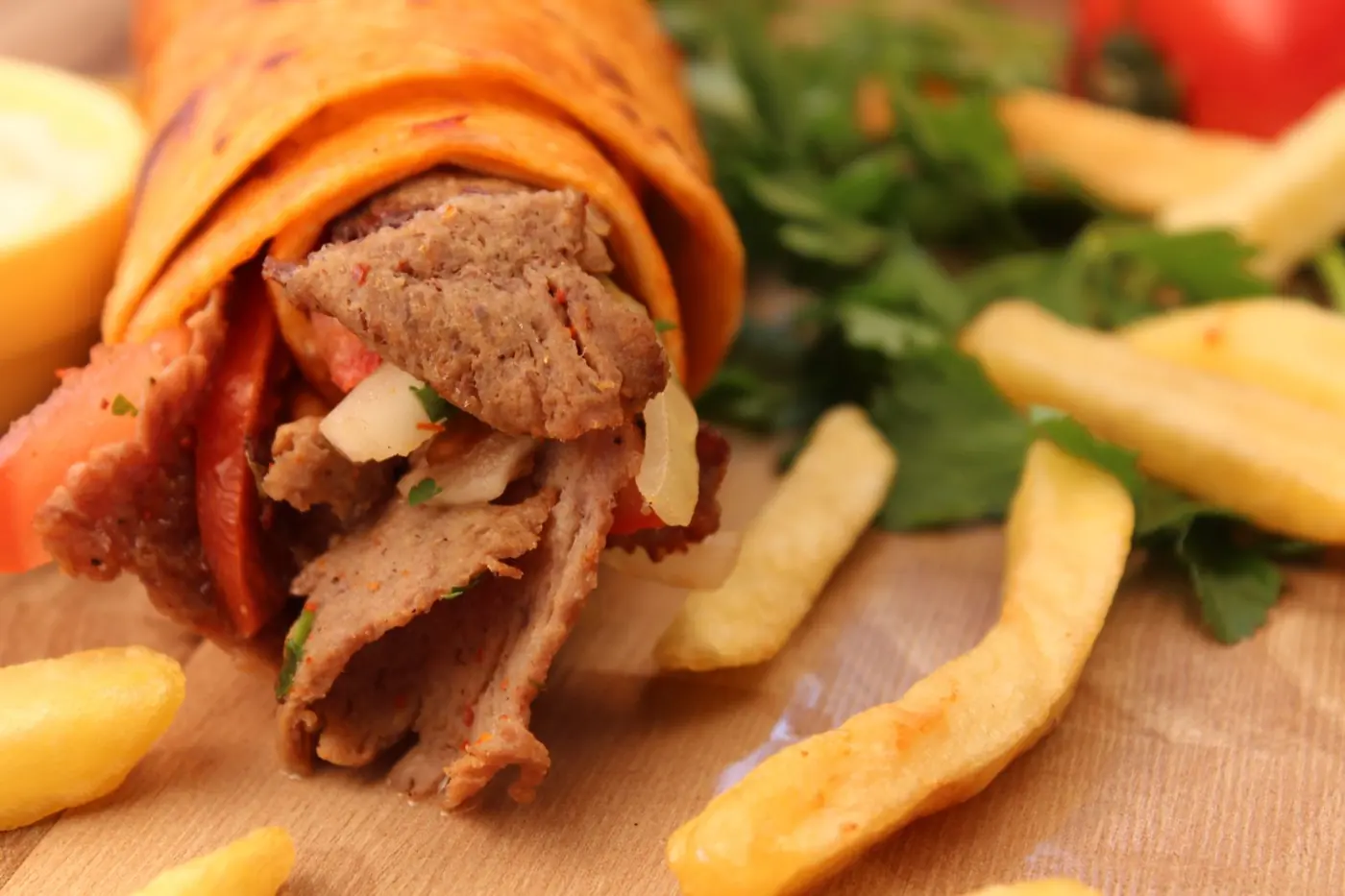 Angeschnittener Döner im Fladenbrot mit Fleischscheiben und Pommes