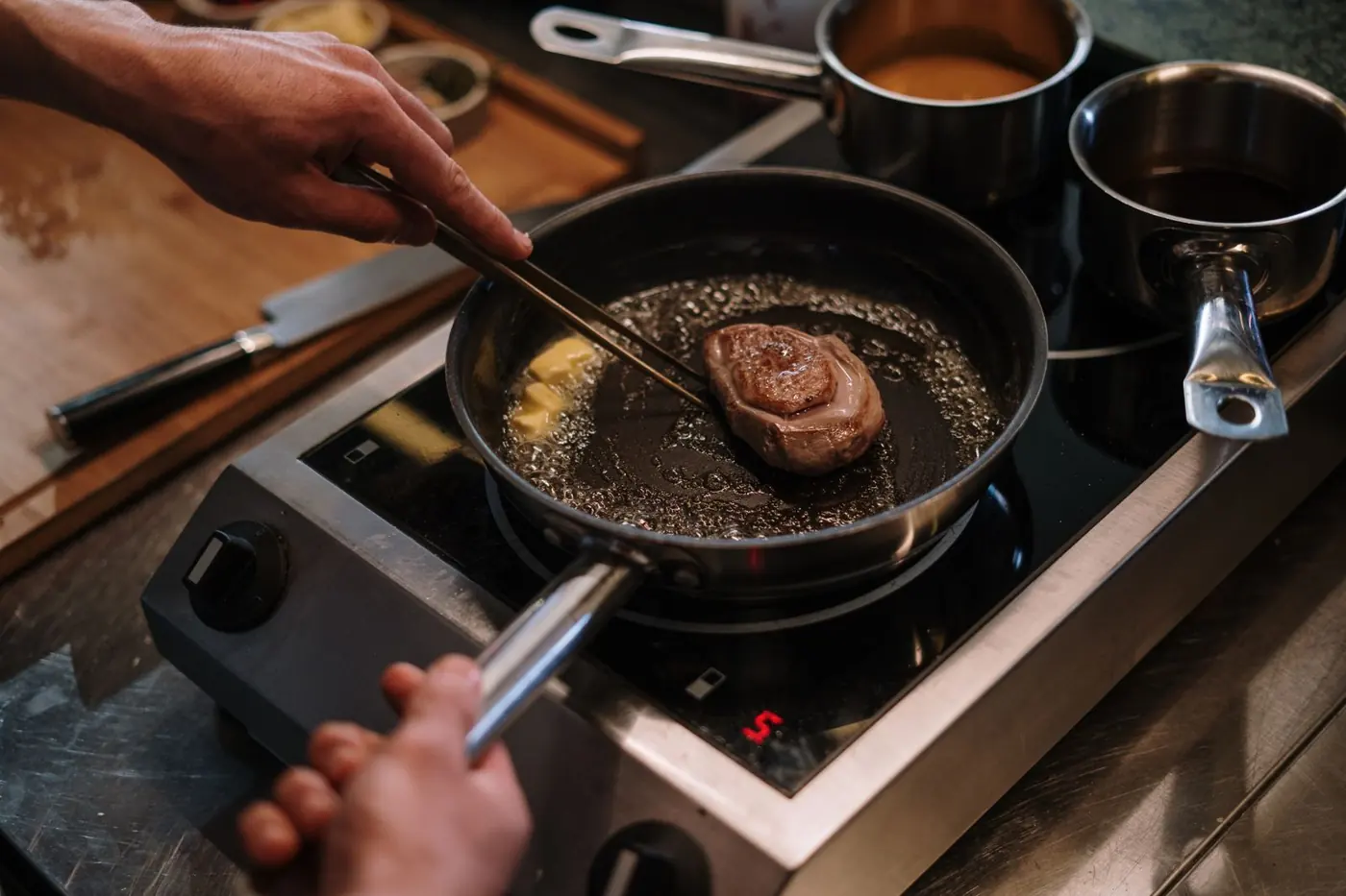 Steak mit brauner Kruste brät mit der Zange in der Pfanne