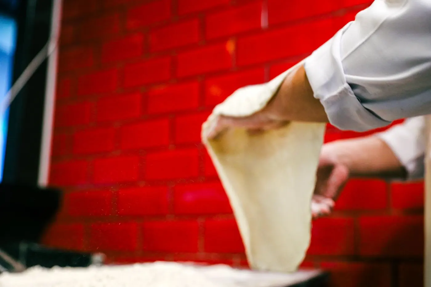 Pizzabäcker zieht den Teig mit den Händen aus