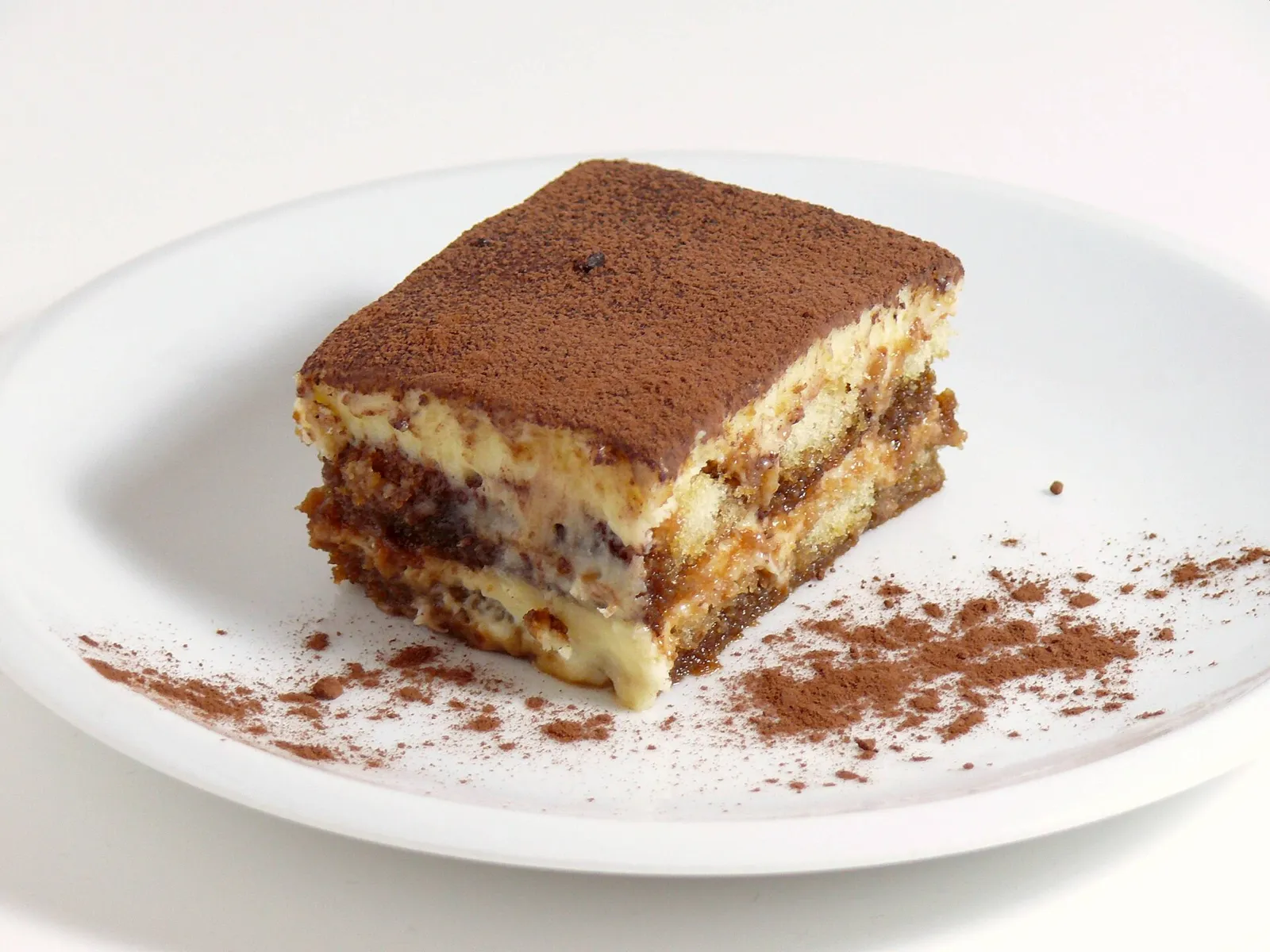 Tiramisu-Stück mit sichtbaren Schichten und Kakao auf einem Teller
