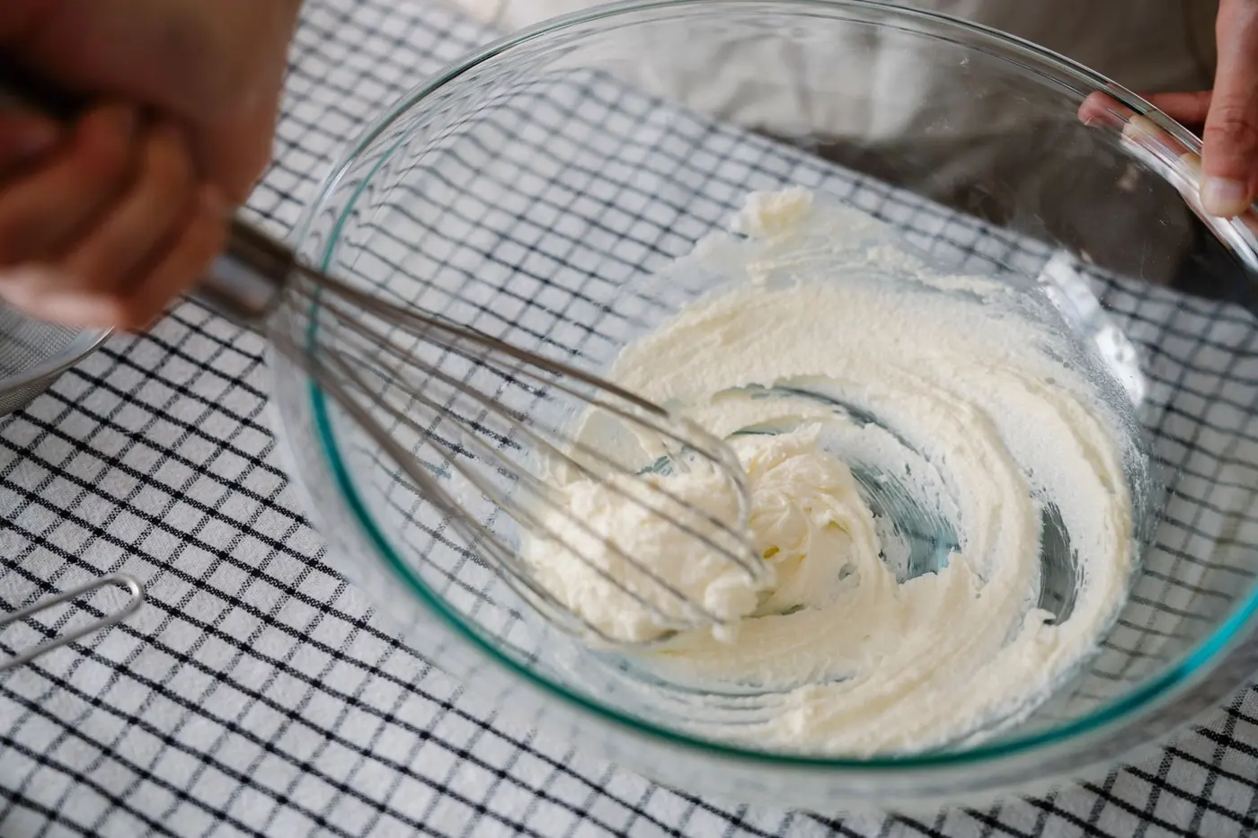 Creme wird mit dem Schneebesen in einer Glasschüssel aufgeschlagen